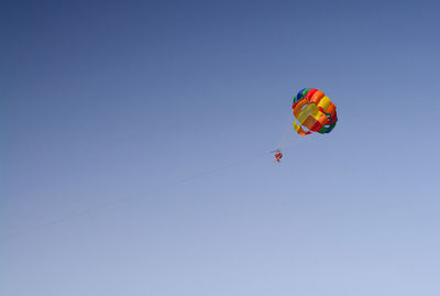 Low angle view of person paragliding against clear sky