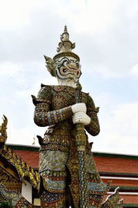 Giant statue standing against building temple in the grand palace in bangkok, thailand.