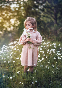 Portrait of a little girl with a bouquet of flowers in nature