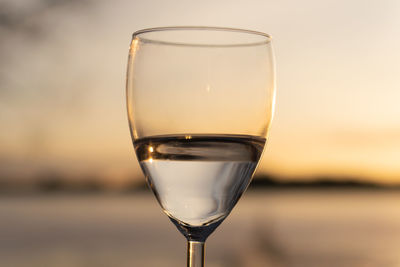 Close-up of beer in glass against sunset sky