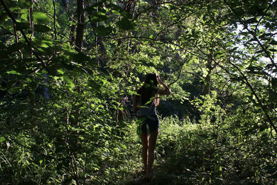 Young woman standing by tree in forest