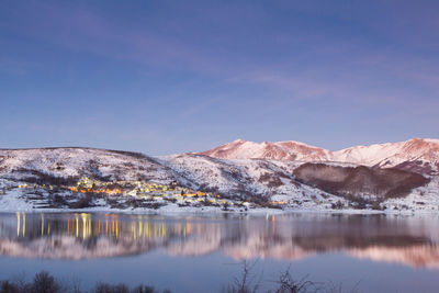 Night view of little village reflected on campotosto lake in abruzzo, italy