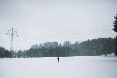 Silhouette person standing on snowy landscape against clear sky