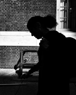 Side view of a woman standing against brick wall