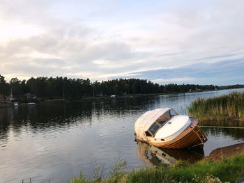 Boat moored on lake against sky