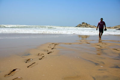 Full length of man on beach against clear sky