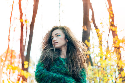 Low angle view of beautiful young woman against trees