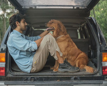 Man with dog sitting in car