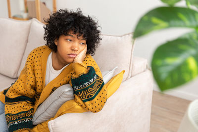 Portrait of young woman sitting on sofa at home