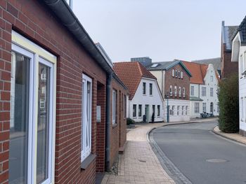 Residential buildings by road against sky