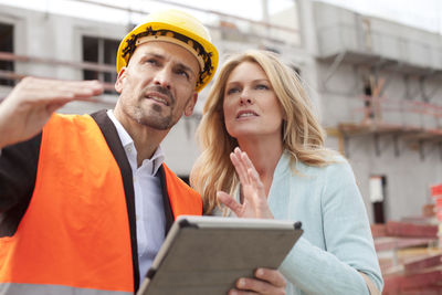 Man with hard hat talking to woman on construction site