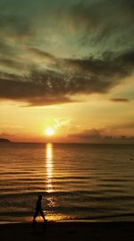 Silhouette person standing on beach against sky during sunset