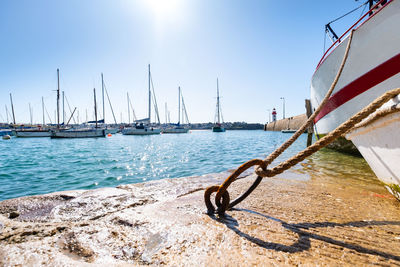 Sailboats moored in sea against sky on sunny day