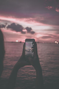 Man photographing on mobile phone against sky