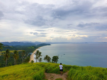 Rear view of man looking at sea against sky