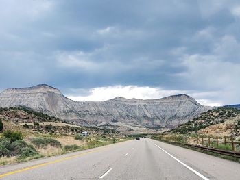 Road leading towards mountains against sky