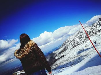 Rear view of woman on snow covered mountain against sky