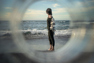 Full length of young woman standing on beach