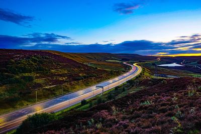 High angle view of winding road on landscape against blue sky