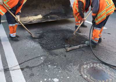 Low section of workers constructing on road in city