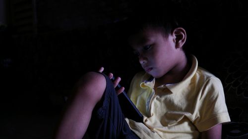 Boy using mobile phone against black background