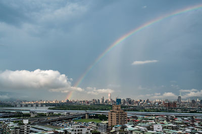 Rainbow over buildings in city against sky