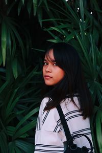 Portrait of beautiful woman standing by plants in park