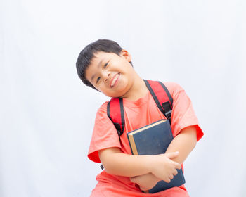 Portrait of smiling boy holding camera over white background