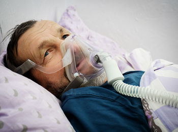 Male patient with oxygen mask lying on bed