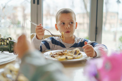 Boy eating food while sitting at table in restaurant