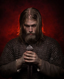 Portrait of viking holding sword against colored background