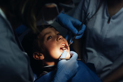 Midsection of dentists examining boy at clinic