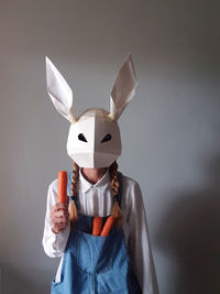 Woman wearing paper rabbit mask holding carrots 