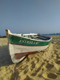 Boat moored on beach against clear sky