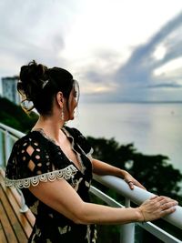 Young woman looking at sea against sky