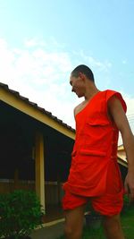 Low angle view of young man looking at camera against sky