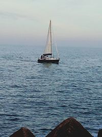 Sailboat sailing on sea against sky during sunset