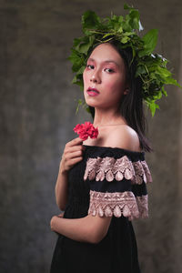 Portrait of a beautiful young woman standing against white wall