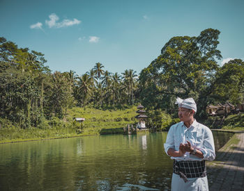 Man standing by lake against trees