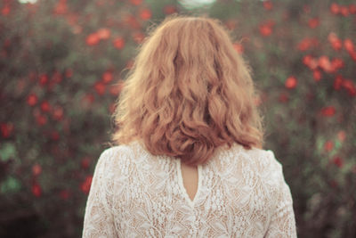 Rear view of woman standing against red flowers