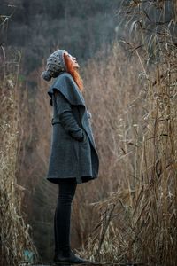 Rear view of woman standing on field in forest