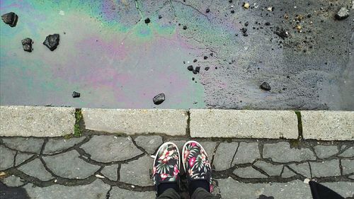 Low section of person wearing shoes on sidewalk