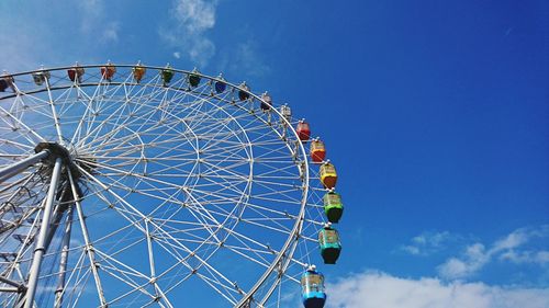 Low angle view of ferris wheel against blue sky