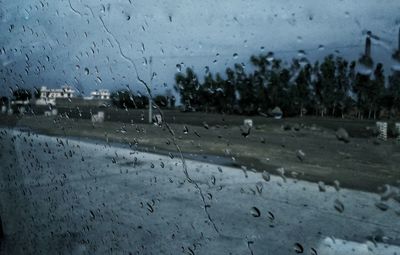 Close-up of waterdrops on glass against road