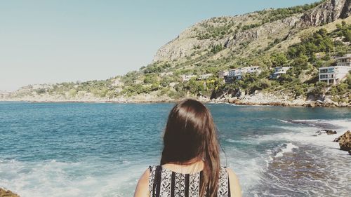 Rear view of woman at beach against sky