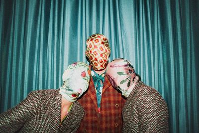 Portrait of person wearing mask against curtain