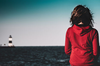 Woman standing by sea against clear sky