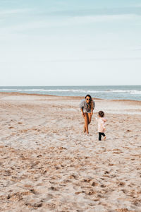 Woman playing with daughter at beach