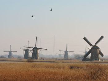 Silhouette of windmill on field against sky