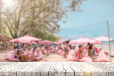 People relaxing on wood against sky